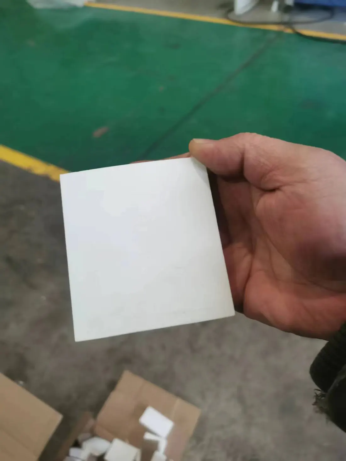 Hand holding a high-alumina ceramic wear tile used in John Finlay dense media cyclone linings